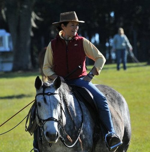 Geneviève Benoit supervisant des élèves à cheval sur un cheval gris foncé